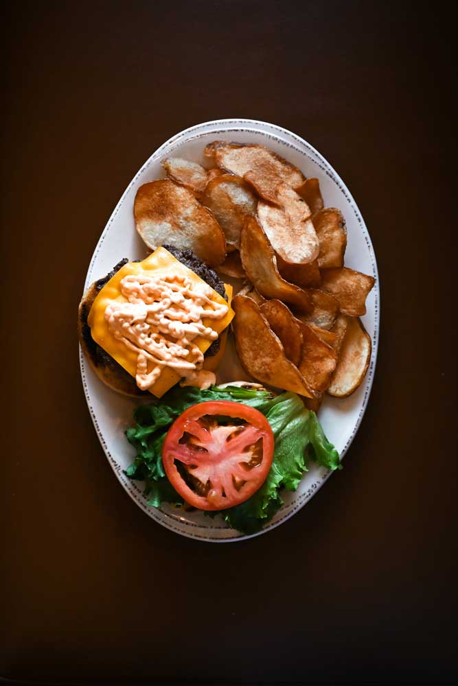 Delicious burger with cheese lettuce tomato and more, served with chips at Mackinaws Grill & Spirits in Green Bay WI.