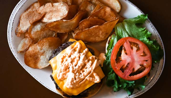 Delicious burger with cheese lettuce tomato and more, served with chips at Mackinaws Grill & Spirits in Green Bay WI.
